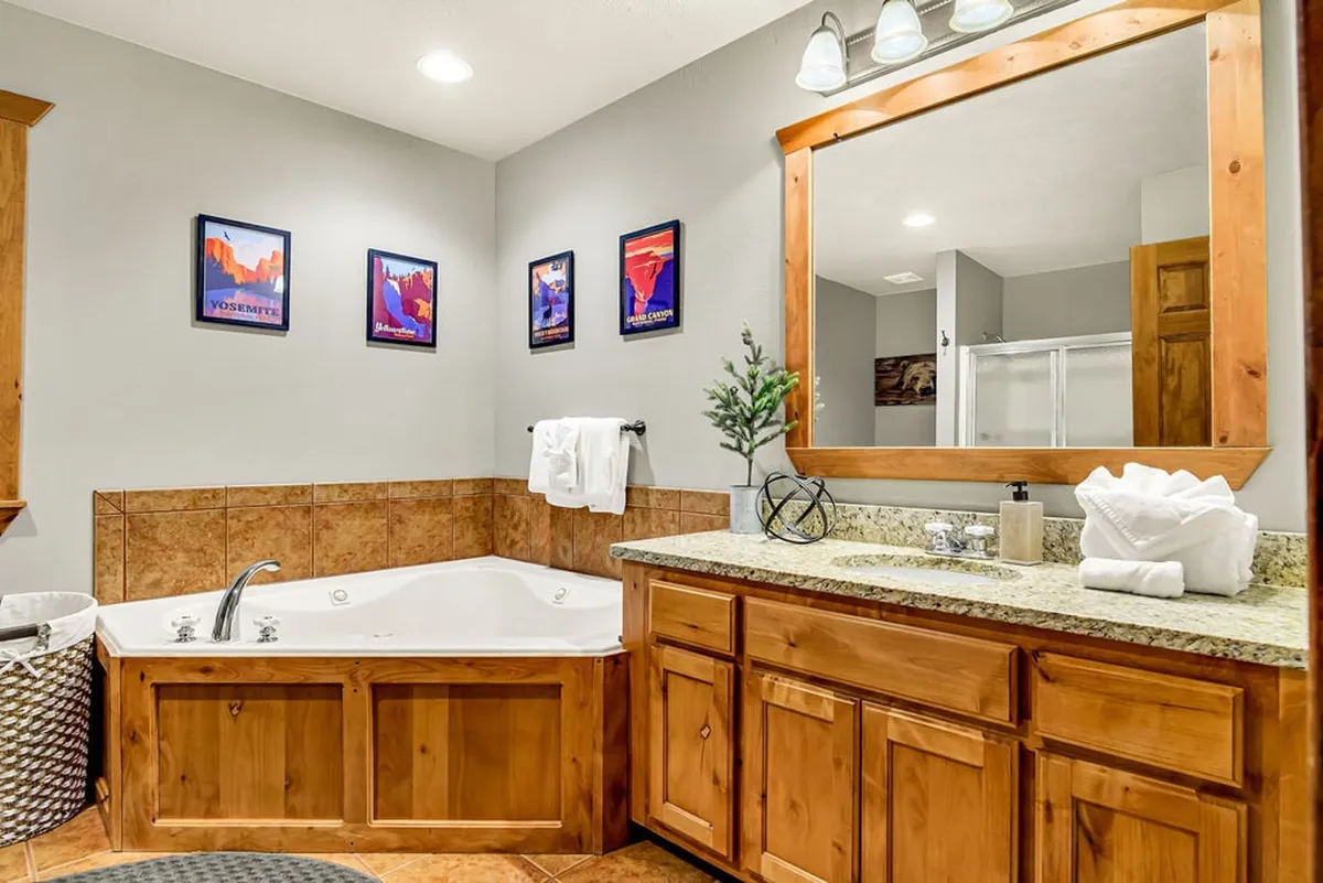 A serene bathroom setting featuring a jacuzzi tub, vanity with sink, and tasteful framed artwork. The space is designed for relaxation and self-care, representing the spa-like ensuite experience described.