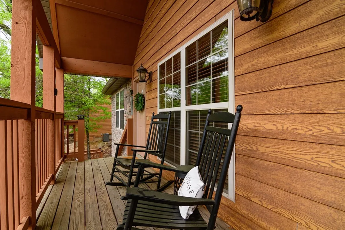 A charming wooden porch with rocking chairs, decorative pillows, and lanterns, set against tranquil outdoor scenery. The setup suggests peaceful mornings and cozy evenings, perfect for sipping coffee or unwinding while enjoying the gentle breeze and birdsong.